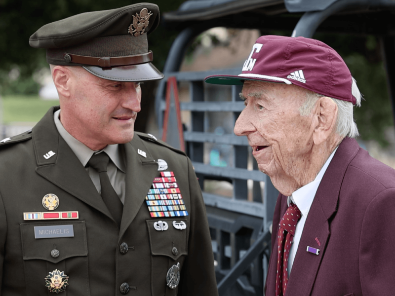 an image of an older man in maroon speaking with a younger man in a U.S. army uniform